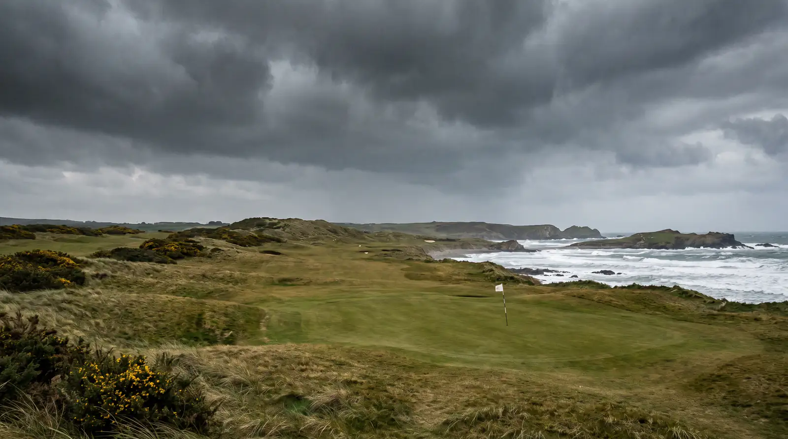Windswept links fairway with flags bent in stiff sea breeze on the day before round one of a major championship