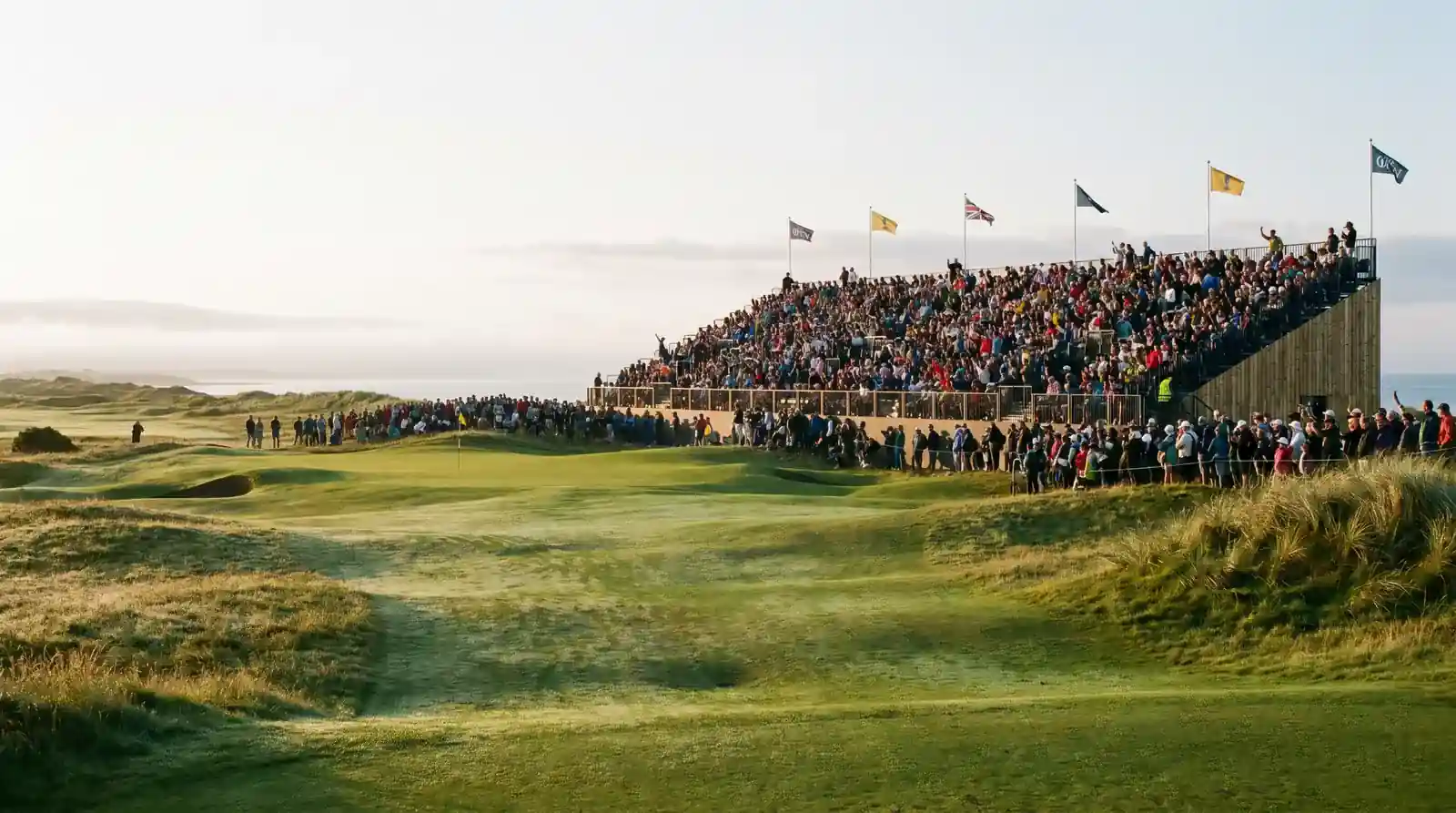 Morning shot from the first tee of a British links course on day one of the Open Championship with grandstand behind