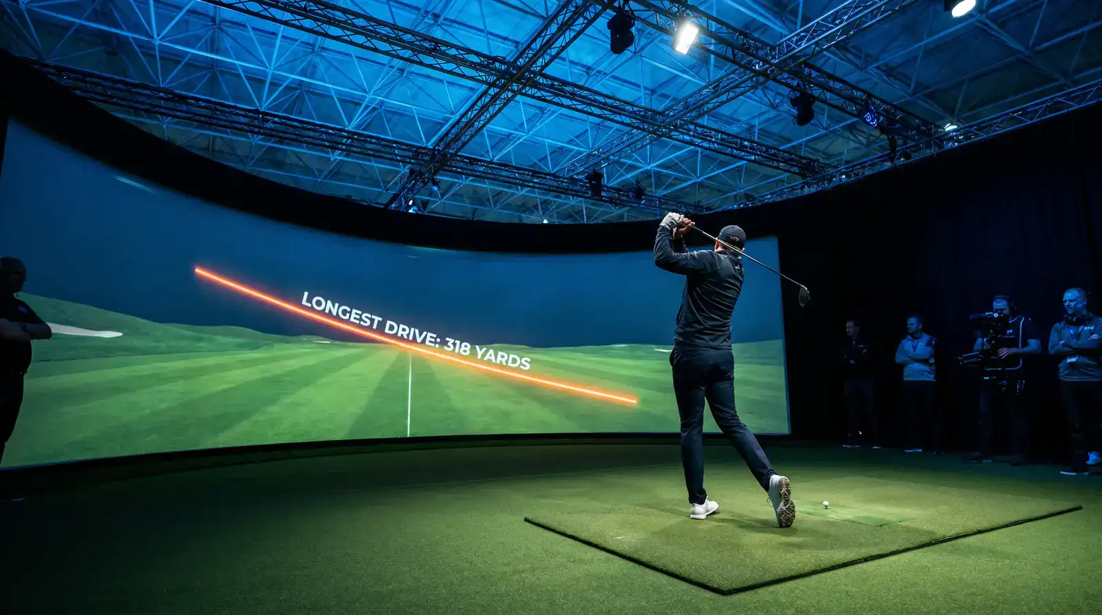 Indoor golf simulator showing a longest-drive measurement on the screen during a TGL-style match night under arena lighting
