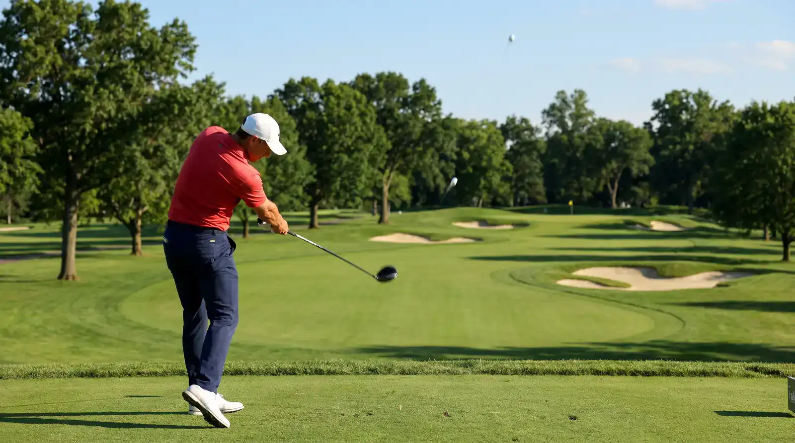 Professional golfer launching a drive from an elevated tee on a parkland US PGA Championship layout
